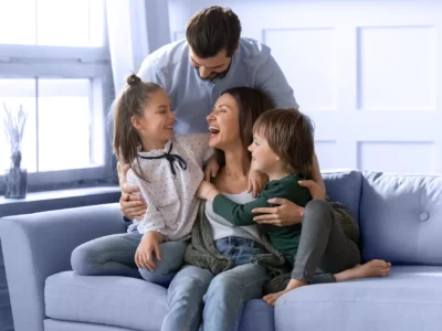 Married couple hugging their children on a sofa.