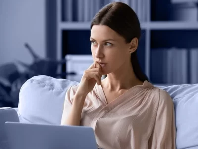 young woman sitting on a sofa deep in thought.